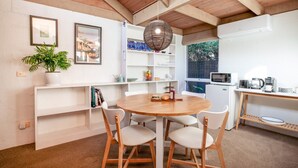 Una cocina moderna con una mesa redonda de madera, sillas blancas, una lámpara colgante y un refrigerador blanco.