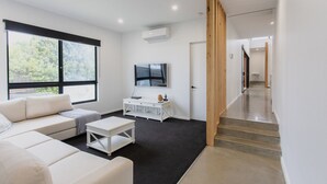 Un salon moderne comprenant un canapé, une table basse, un téléviseur et un escalier menant à un autre espace.