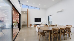 Un intérieur moderne comprenant un coin repas, un téléviseur fixé au mur et une vue sur l’extérieur.