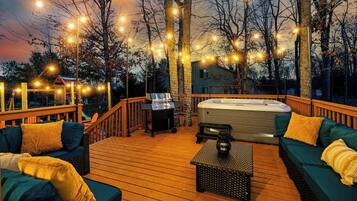 A wooden deck with outdoor seating, a hot tub, and string lights.