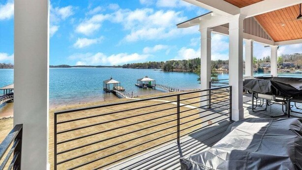 Un balcone con vista su un lago, un gazebo e un'area barbecue.