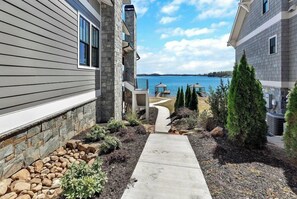 A residential property with a stone exterior, a stone pathway leading to a deck, and a view of a lake. - Morning Mist on Keowee (Seneca)