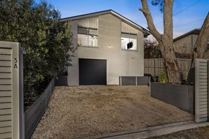 Ein modernes, zweistöckiges Haus mit Garage, einem Schotterweg und einem Holzzaun.