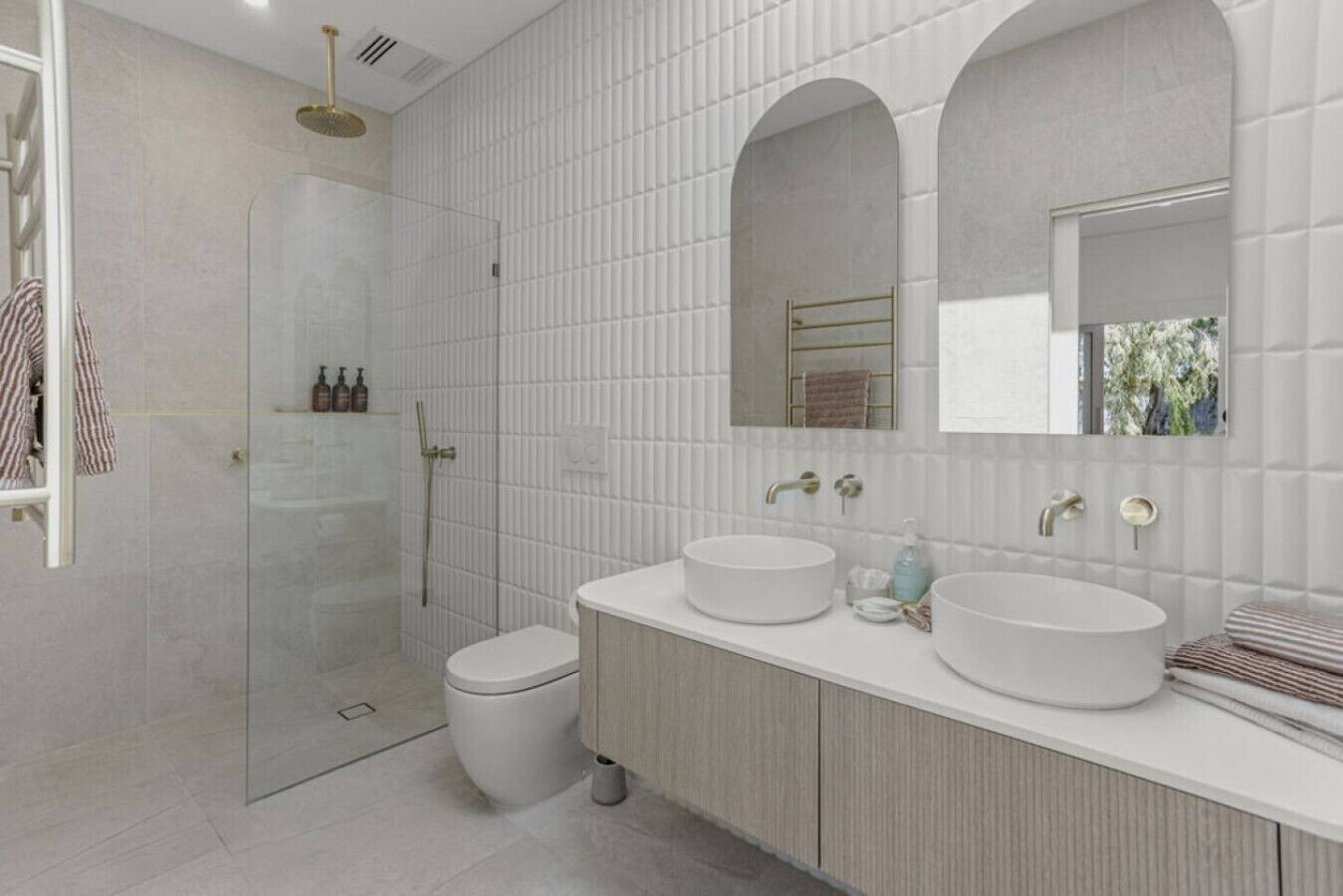 A modern bathroom with a glass-enclosed shower, two sinks, and a large mirror.