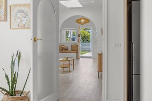 A hallway leading to a living area with a sofa, a table, and a hanging light fixture. - Coastal Waters - Spa, Sleeps 8, Newly Renovated (499538) (Ocean Grove)