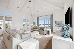 A spacious living room with a high ceiling, large windows, and a flat-screen TV. - Sleeps 22! Private Pool, LSV/Golf Cart, & GULF VIEWS! Steps to Beach! (Santa Rosa Beach)