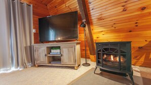 A cozy room with a television on a wooden cabinet, a fireplace, and curtains. - Little Bear Cabin Robbinsville NC (Robbinsville)