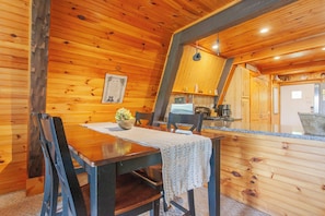 A wooden interior with a dining table, chairs, a kitchen area, and a wooden ceiling. - Little Bear Cabin Robbinsville NC (Robbinsville)
