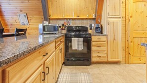 A kitchen with wooden cabinets, a stove, a microwave, and a coffee maker. - Little Bear Cabin Robbinsville NC (Robbinsville)