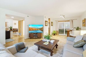 A modern living room with a flat-screen TV, a coffee table, sofas, and a dining area. - Sleeps 8 | 4BR | Fire Pit | Near UCSD & La Jolla (San Diego)