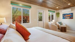 Ein Schlafzimmer mit einem großen Bett, einem Schreibtisch, einem Stuhl und einem Fenster mit Blick ins Freie.