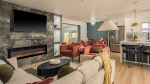 Uma sala de estar moderna com lareira, uma TV de tela plana e um espaço de refeições com banquetas.