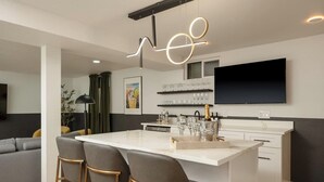 Uma cozinha moderna com ilha central, banquetas, televisão de tela plana e adega.