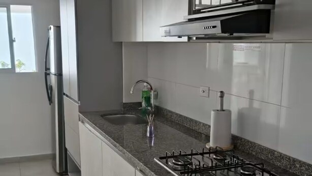 A modern kitchen with a stainless steel refrigerator, a microwave, a gas stove, and a window. - Enjoy a peaceful escape in the Coffee Region. (pereira)