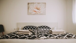 Una cama con una colcha estampada, dos almohadas y una obra de arte colgada en la pared.
