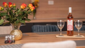 Una mesa con una botella de vino rosado, dos copas de vino vacías, un jarrón con rosas y saleros y pimenteros.