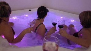 Un grupo de personas en un jacuzzi con iluminación morada, sosteniendo copas de vino.
