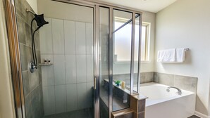 A modern bathroom with a glass-enclosed shower, a bathtub, and a vanity with a mirror. - Spacious 4-bedroom house in friendly neighborhood in Round Rock (Round Rock)