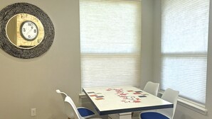 A dining area with a table and chairs, a wall clock, and two windows with blinds. - Spacious 4-bedroom house in friendly neighborhood in Round Rock (Round Rock)