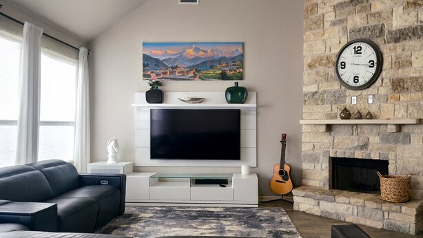 A living room with a flat-screen TV, a fireplace, a guitar, and a painting on the wall. - Spacious 4-bedroom house in friendly neighborhood in Round Rock (Round Rock)