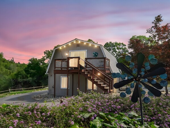A two-story house with a balcony, a staircase, and a windmill in the foreground.