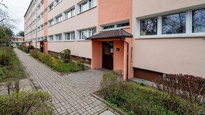A multi-story residential building with a brick pathway, greenery, and a small entrance with a door marked '16-30'. - Limanowskiego Harmony Apartment (Łódź)