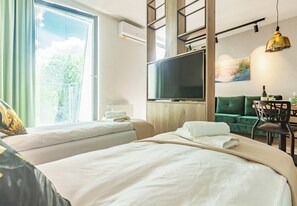 A hotel room with two beds, a TV, a dining area with a table and chairs, and a view of the outdoors. - Sopot City Comfort Apartment #2 (Sopot)