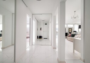 A modern interior with a hallway leading to a living area, featuring a white color scheme and a chandelier. - Grzybowska 14th Floor Royal Apartment (Warszawa)