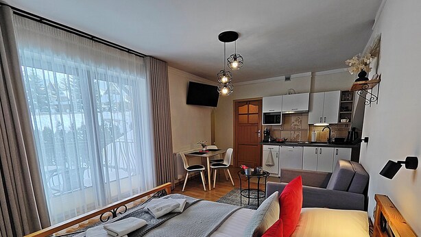 Une chambre d’hôtel comprenant un lit, une petite table, un canapé, un coin cuisine et un coin repas.