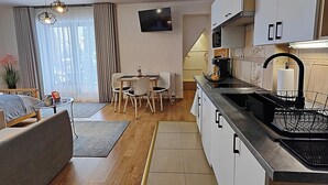 Une cuisine moderne avec un coin repas, un téléviseur à écran plat et un escalier menant à l’étage supérieur.