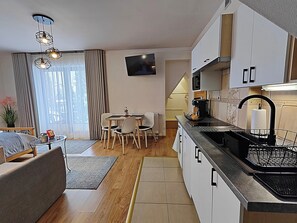 A modern kitchen with a dining area, a flat-screen TV, and a staircase leading to an upper level. - Willa u Bachledów Studio #4 (Zakopane)