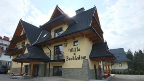 Un bâtiment à deux étages doté d’un balcon, d’une enseigne indiquant « Willa u Bachledom » et d’une allée gravillonnée.