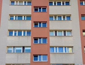 Ein mehrstöckiges Gebäude mit gleichmäßig angeordneten Fenstern und einem zentralen, vertikalen Abschnitt.