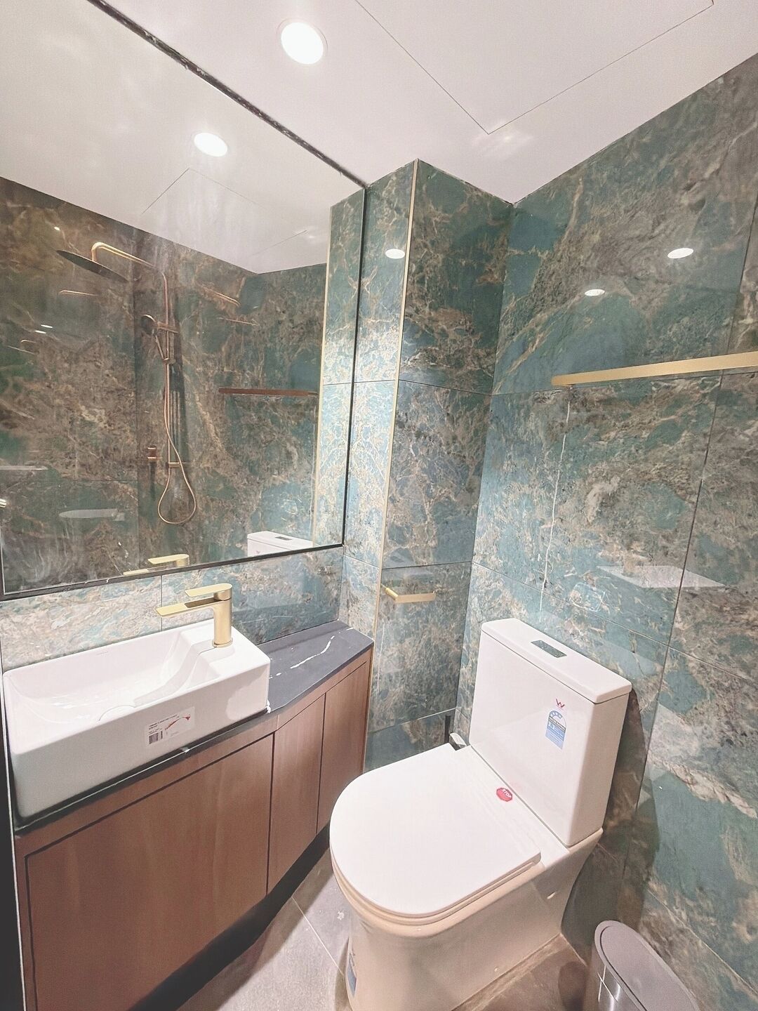 Een badkamer met een wit wastafel, toilet en een grote spiegel.