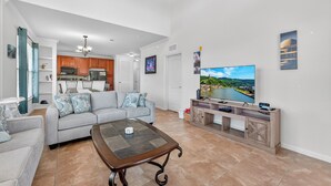 Una sala de estar moderna con un sofá gris, una mesa de centro y un televisor sobre un mueble de madera.