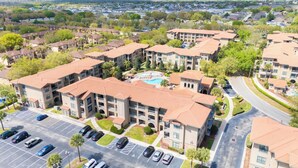 Un complejo residencial con varios edificios de apartamentos, una piscina y un estacionamiento.