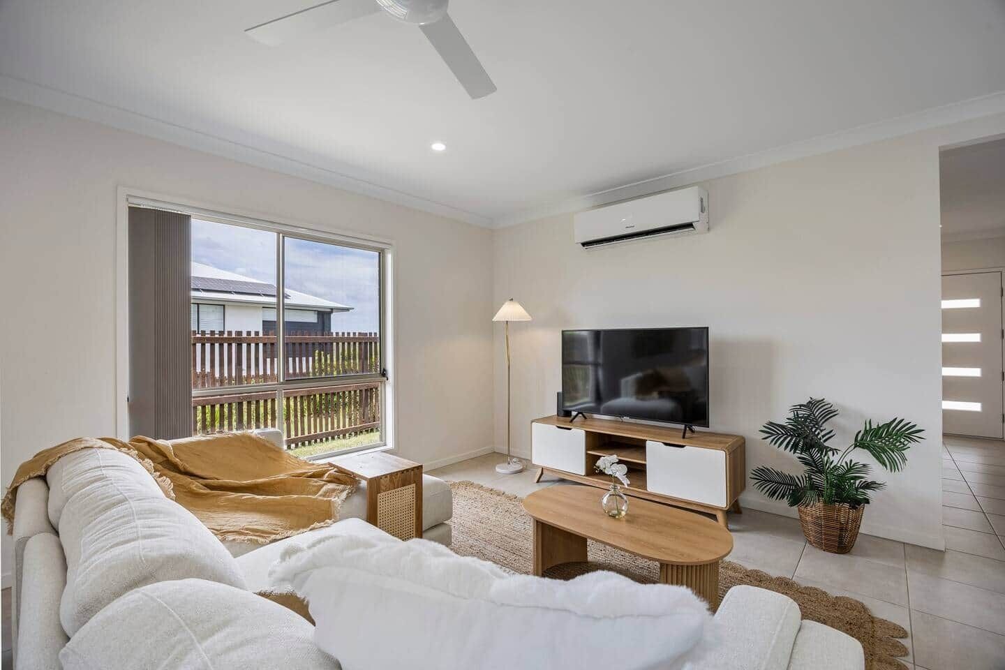 Una sala moderna con sofá, televisor y vistas al balcón.