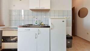 Eine kleine Küche mit Kühlschrank, Backofen und Spüle.