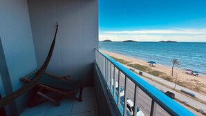 Ein Balkon mit einer Hängematte, Blick auf den Strand und einem klaren Himmel.