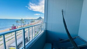 Ein Balkon mit Blick auf den Strand, Palmen und ein Berg.
