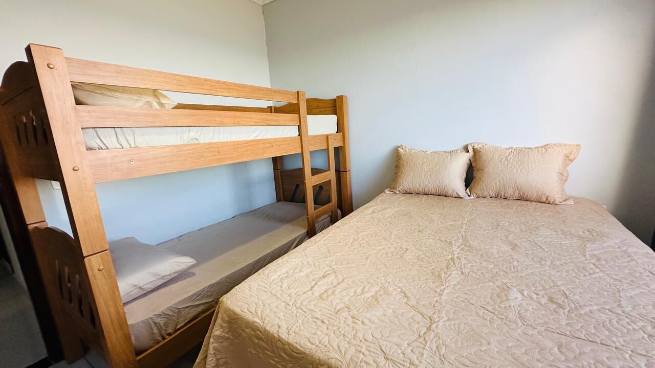 Una litera con una cama inferior y una cama individual, ambas con ropa de cama color beige.
