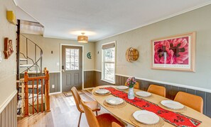 A dining area with a long table set for four, a staircase, and a door leading outside. - 6.5 Acre Retreat w/ Natural Spring + Mountain View (Durango)