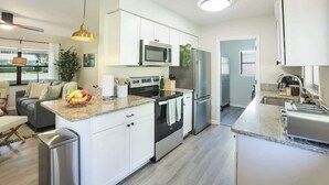 Una cocina moderna con armarios blancos, electrodomésticos de acero inoxidable y encimera de granito.