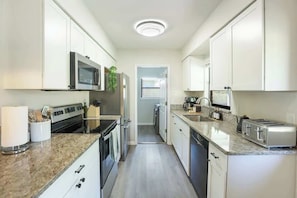 Una cocina moderna con armarios blancos, electrodomésticos de acero inoxidable y encimeras de granito.