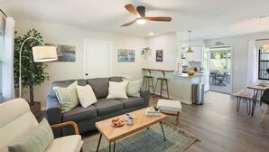 Una sala de estar moderna con un sofá, una mesa de centro y una zona de comedor con una cocina al fondo.
