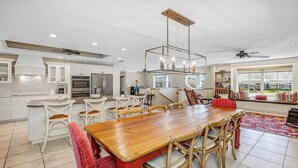 Una cocina moderna con armarios blancos, una mesa de comedor de madera y un ventilador de techo.