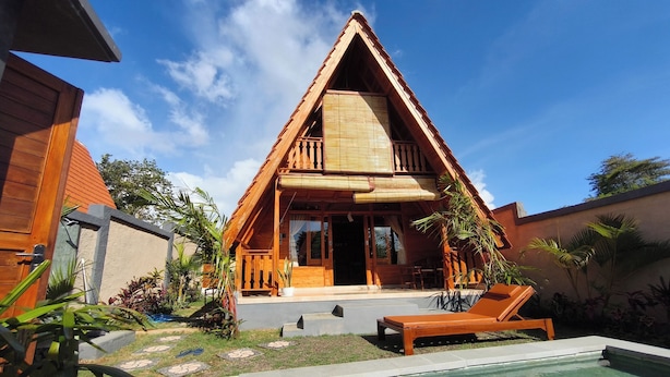 A wooden villa with a triangular roof, a swimming pool, and a garden with tropical plants. - D'Cabin Villa Uluwatu (Pecatu)
