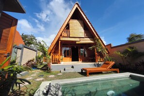 A wooden villa with a triangular roof, a swimming pool, and a garden with tropical plants. - D'Cabin Villa Uluwatu (Pecatu)