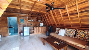 A wooden interior with a kitchen, a sofa, and a ceiling fan. - D'Cabin Villa Uluwatu (Pecatu)