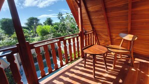A wooden balcony with a view of greenery and a clear sky. - D'Cabin Villa Uluwatu (Pecatu)